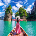 Beautiful girl standing on the boat and looking to mountains in
