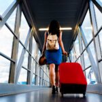 Young girl traveler walking with carrying hold suitcase in the airport.