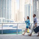 focused_180533598-stock-photo-couple-strolling-waterfront-carrying-shopping-629×420