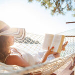 Woman in a hammock with book on summer day