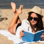 woman-with-sunglasses-reading-book-beach_23-2148700280